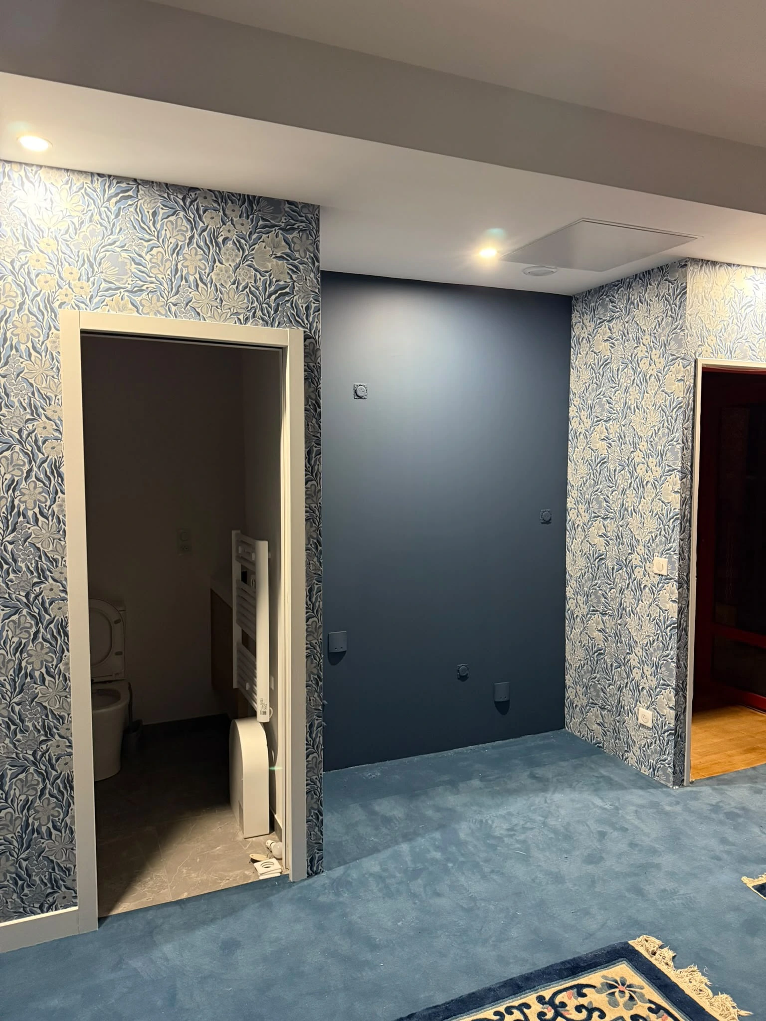 Même chambre finie avec papier peint à motifs floraux et moquette bleue