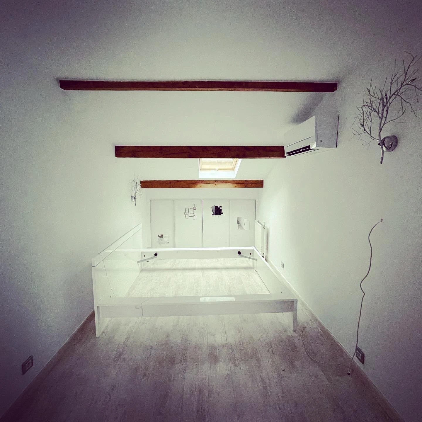Même chambre sous combles rénovée, murs blancs et poutres apparentes