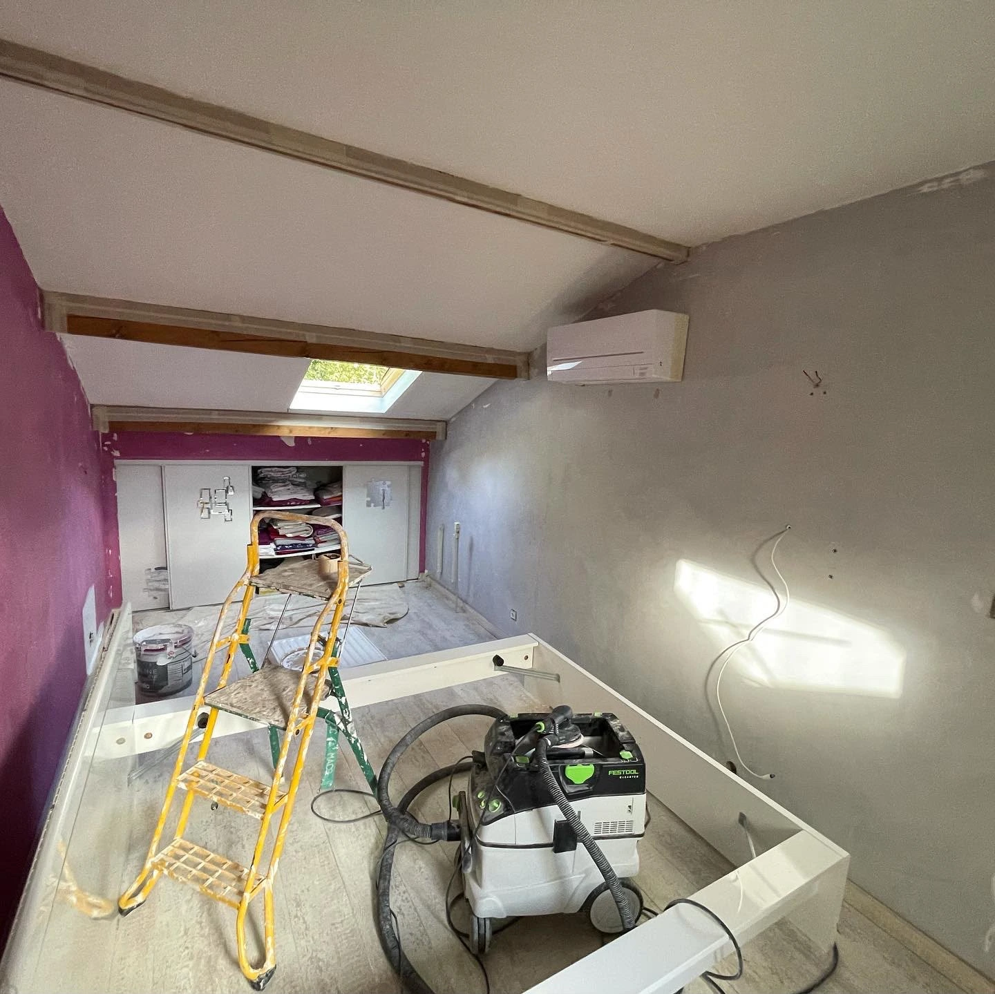 Chambre sous combles en travaux, mur rose et outillage