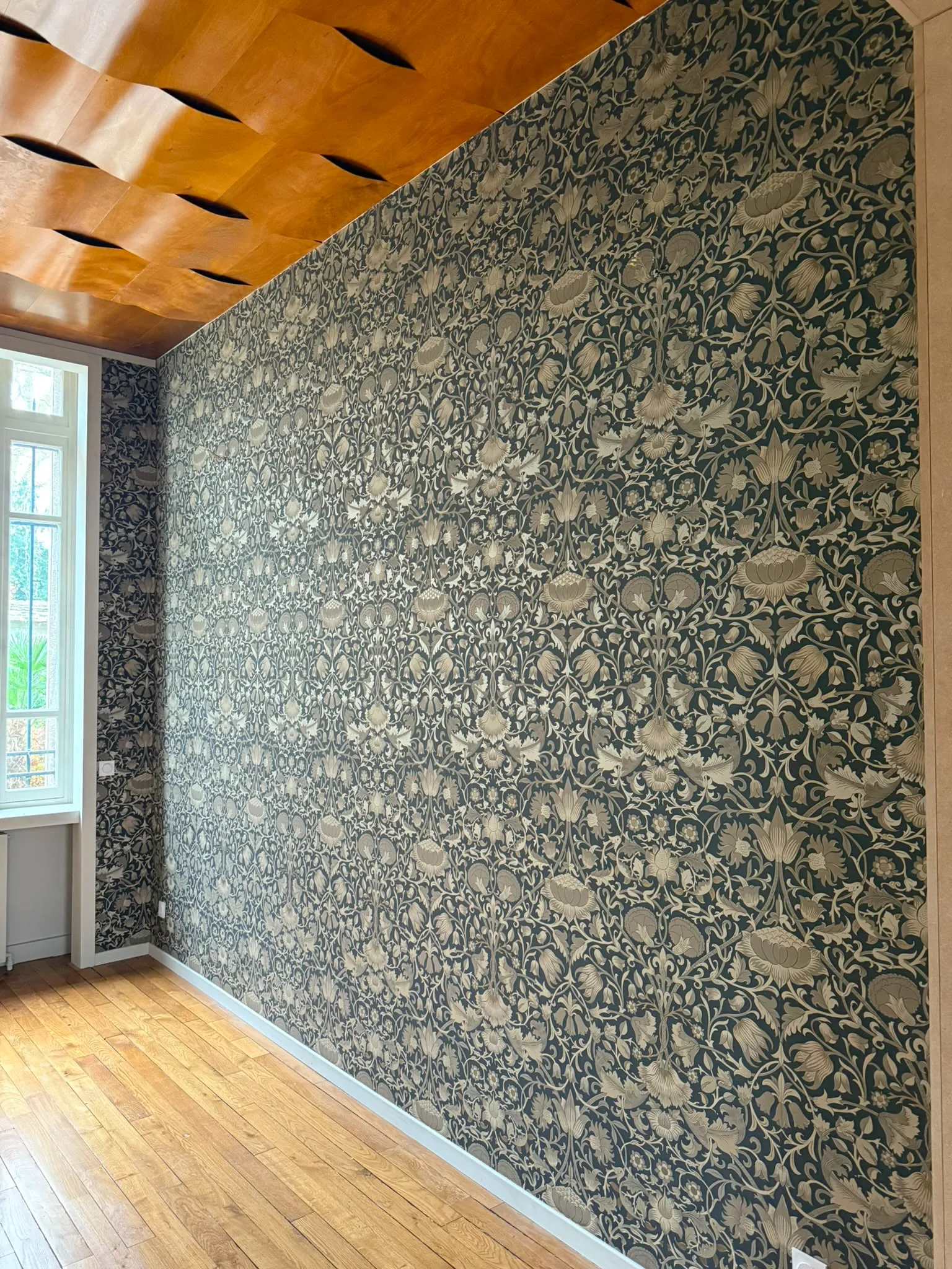 Mur habillé d'un papier peint à motifs floraux vert foncé